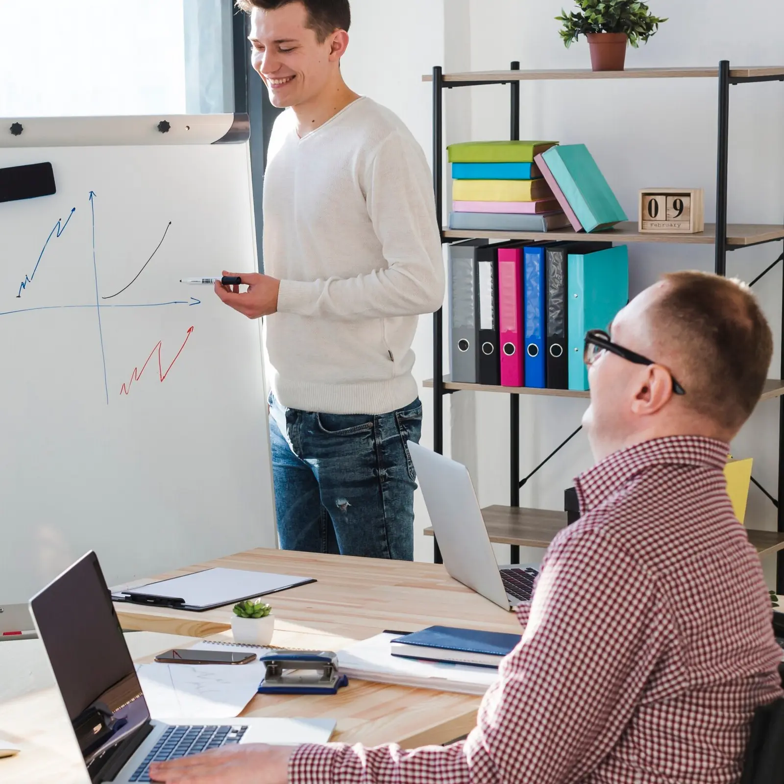 Person in a training session, interacting with a mentor or trainer in a modern classroom or workshop setting